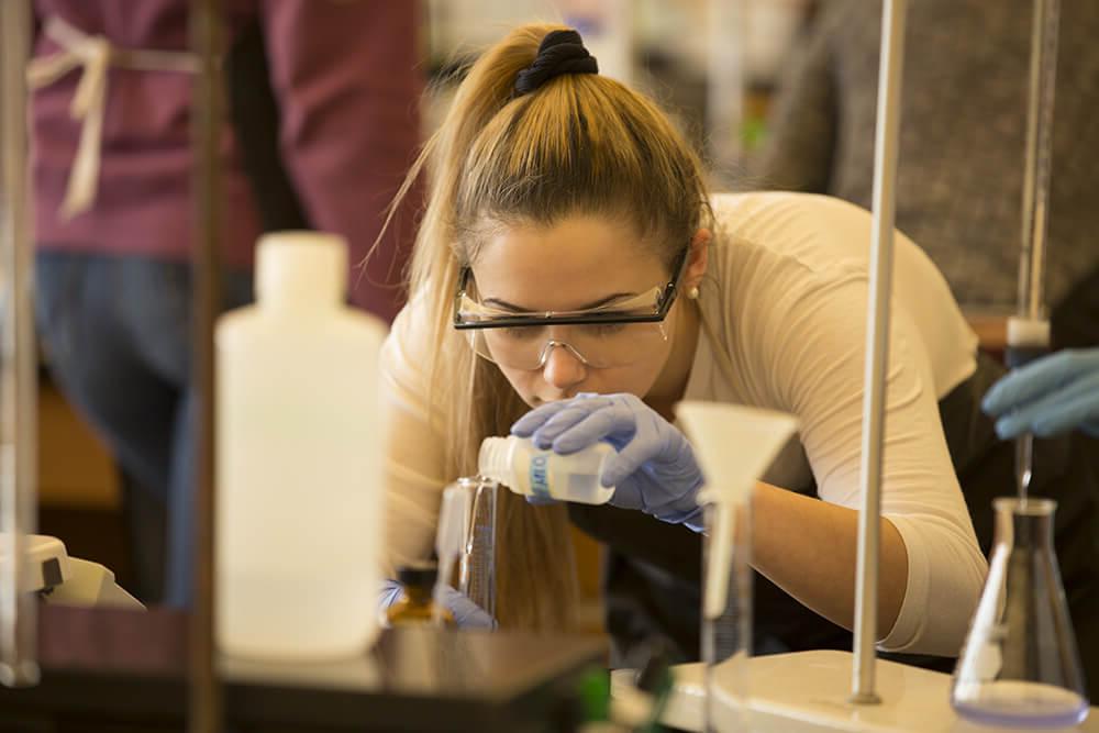 Photo of a student pouring chemicals in a Lyons Center lab