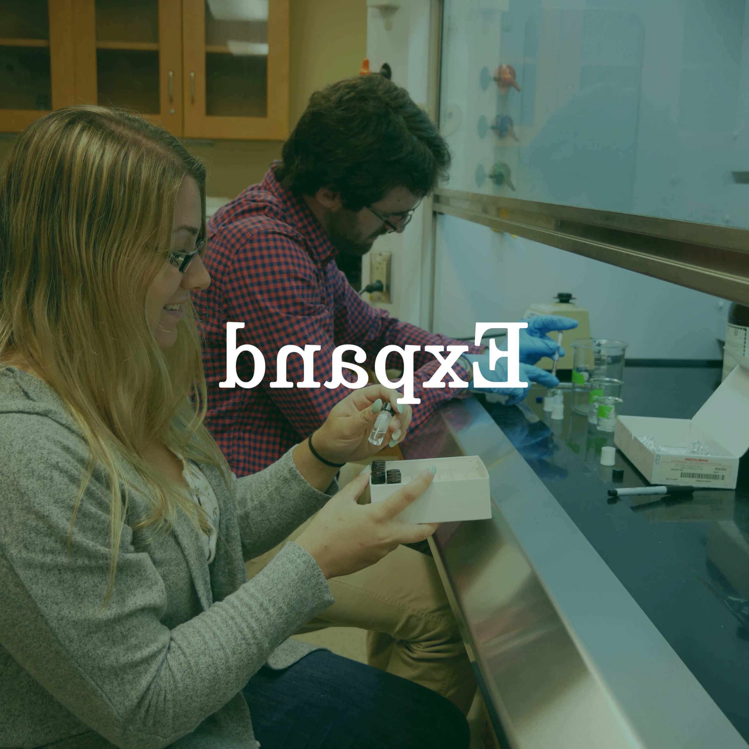 Photo of students working at a lab bench with a text overlay that reads "Expand."